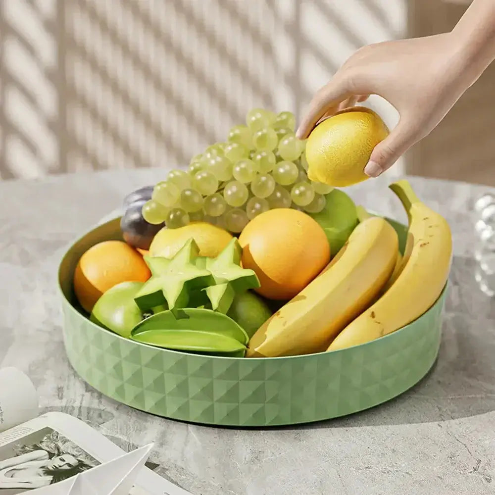 A hand placing a lemon into a 360-degree spice organizer filled with various fruits on a table.