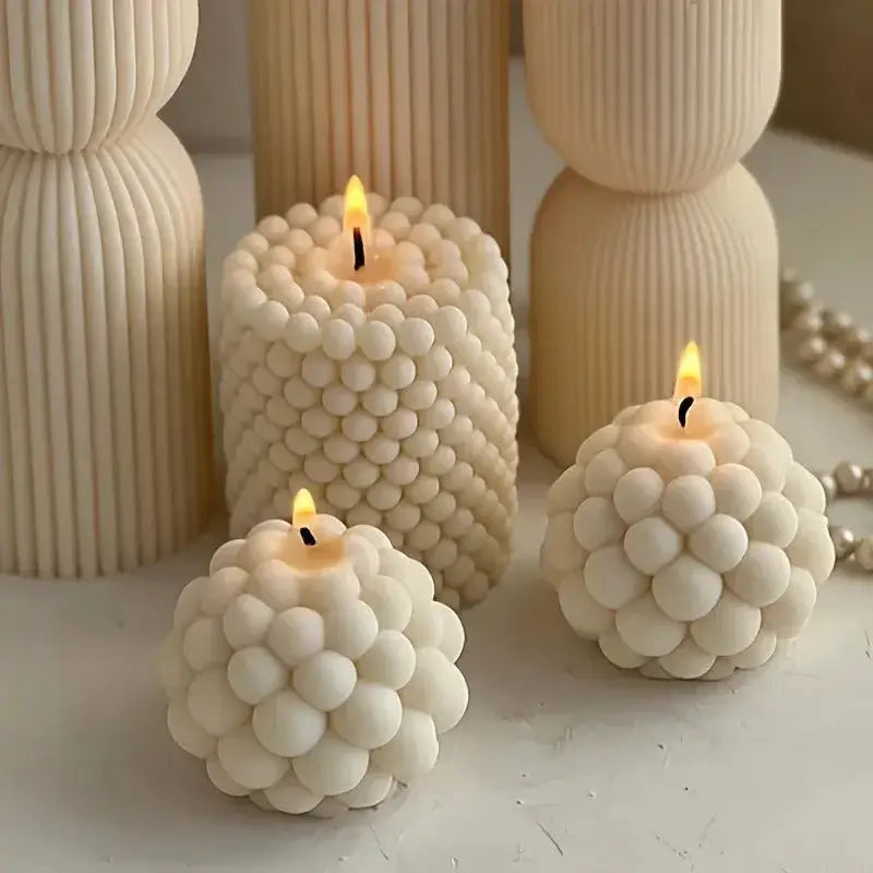 Three elegant white bubble candles made using the bubble candle mold, showcasing unique round and cylindrical designs.