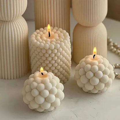 Three elegant white bubble candles made using the bubble candle mold, showcasing unique round and cylindrical designs.